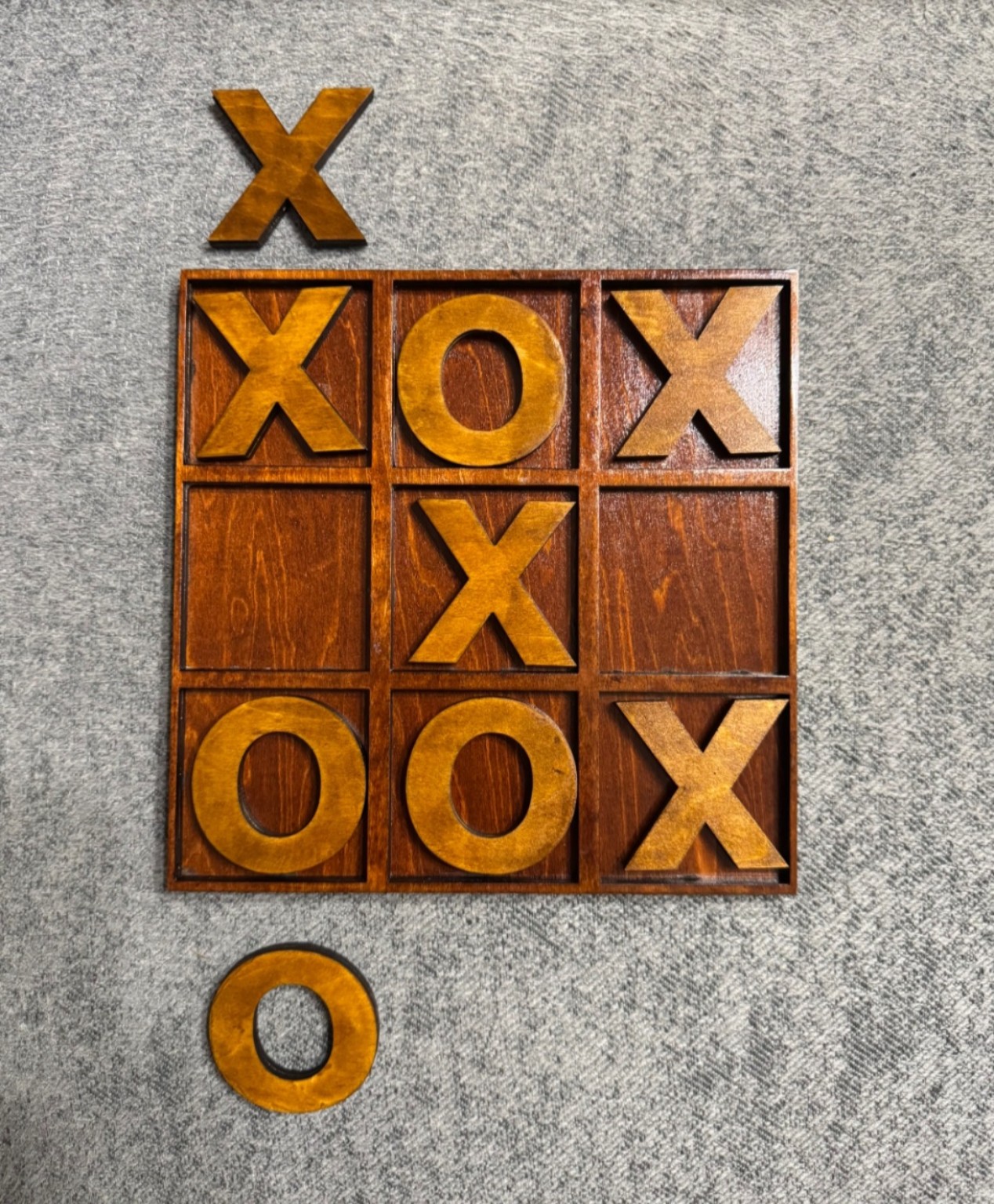 Dark wooden tic tac toe board with removable golden-brown X and O playing pieces