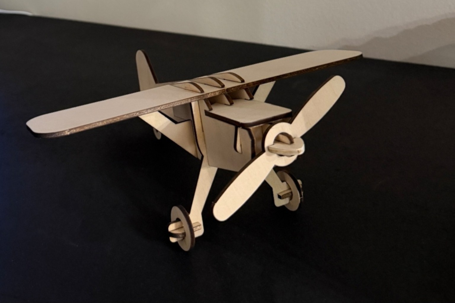 Natural wood high-wing model airplane with propeller and landing gear