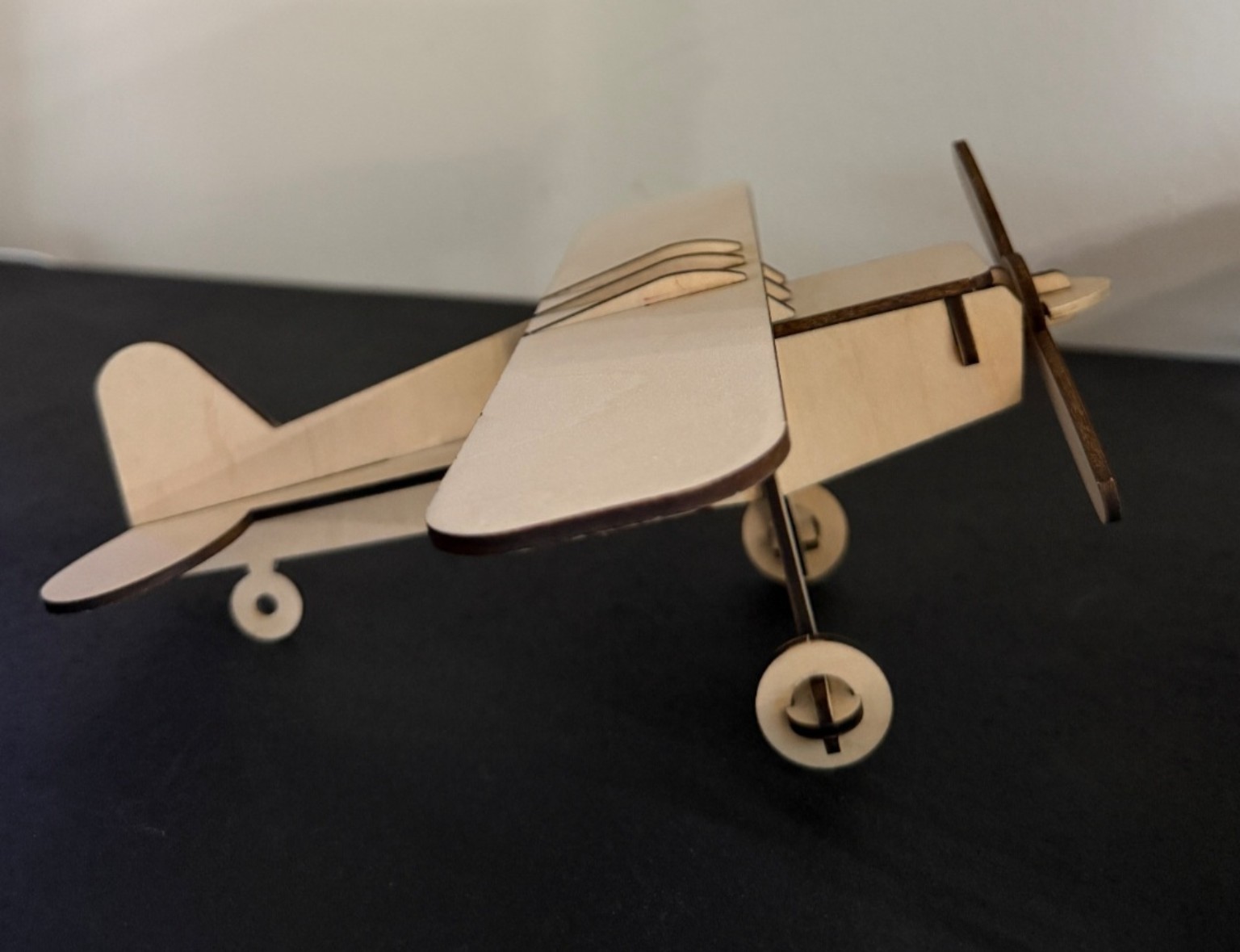 Natural wood high-wing model airplane with propeller and landing gear