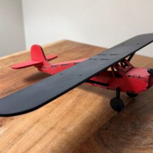 Red and black wooden model airplane with black wing, propeller and landing gear