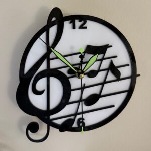 Black treble clef and musical note wall clock on a light face with green-accented hands