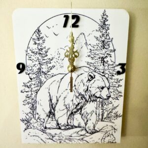 White acrylic wall clock with detailed black bear, forest and mountain scene, black numbers and gold-toned clock hands