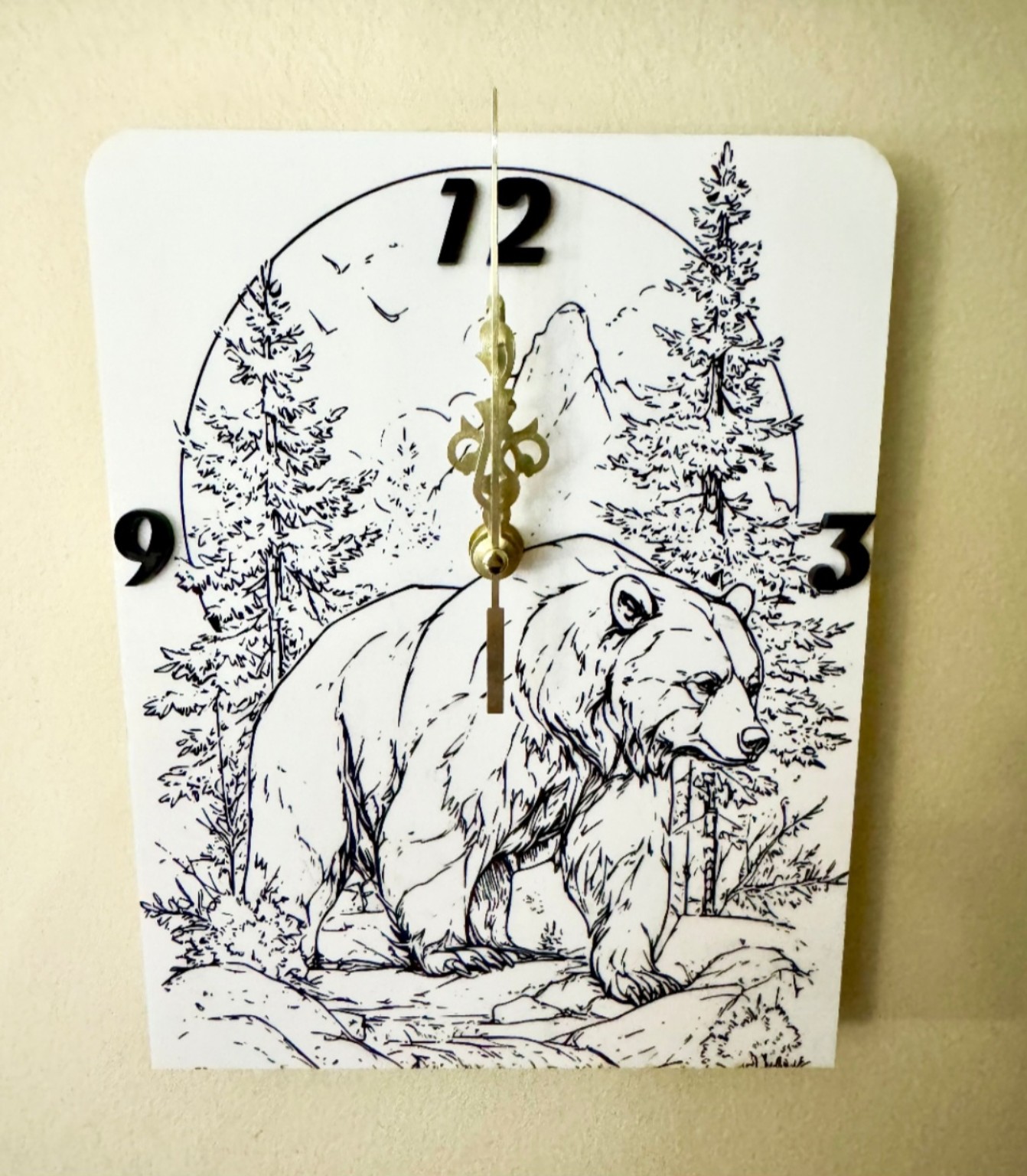 White acrylic wall clock with detailed black bear, forest and mountain scene, black numbers and gold-toned clock hands