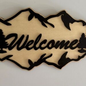 Light wooden Welcome sign with black mountain and evergreen silhouettes and bold lettering