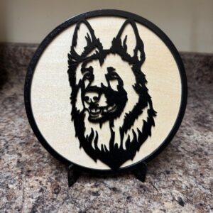 Round 7½-inch wooden German Shepherd portrait decoration in black and natural wood tones on a black display stand