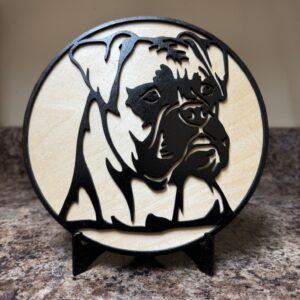 Round 7½-inch wooden Boxer dog portrait decoration in black and natural wood tones on a black display stand